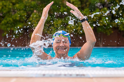 Portrait of smiling woman splashing in swimming pool