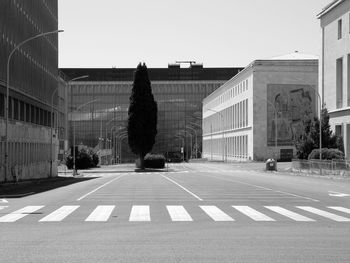 Road by buildings against clear sky in city