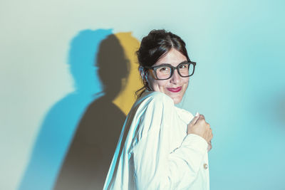 Portrait of young woman standing against wall