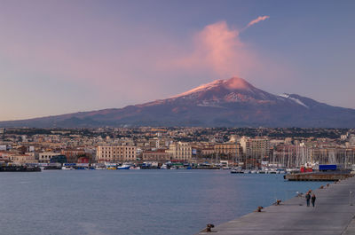Aerial view of townscape by sea against sky