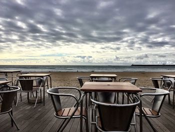 Empty chairs against cloudy sky