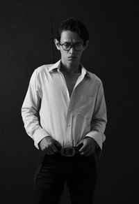 Young man standing against black background