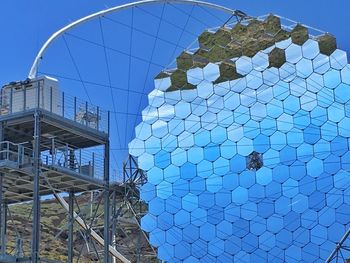 Low angle view of glass building against blue sky