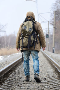 Full length rear view of man walking on railroad tracks