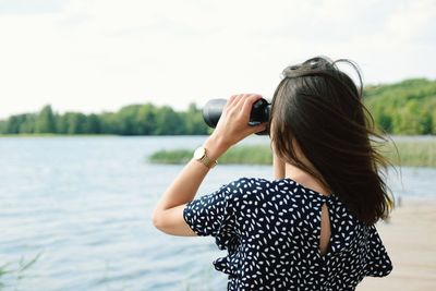 Rear view of woman photographing against sky