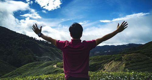 Rear view of woman with arms raised against mountains