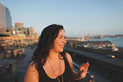 Smiling woman standing by railing against sky