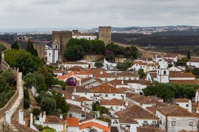 High angle view of houses in medieval town of obidos with castle against sky