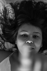 Close-up portrait of young woman lying on bed