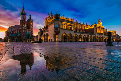 Amazing and romantic view of krakow medieval market square at sunrise with reflection in the puddle