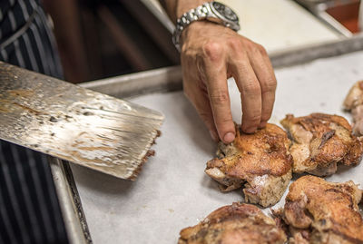 Cropped hand of male chef preparing meat in kitchen