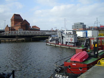 Boats moored on river in city against sky