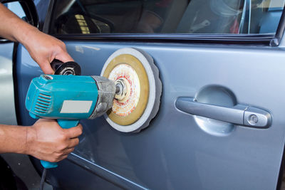 Cropped hands of man polishing car in auto repair shop