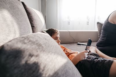 Rear view of siblings sitting on sofa at home