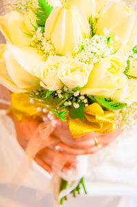 Midsection of bride holding rose bouquet