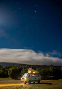 Car on road amidst field against sky at night