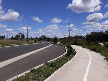 Empty road by street against sky