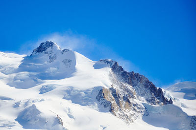 Scenic view of snow covered mountains against clear blue sky