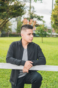 Enterprising man standing by the white wooden fence with his hands on the fence