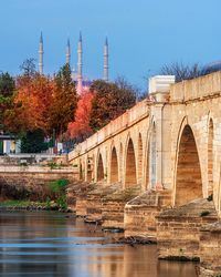 Arch bridge over river against clear sky