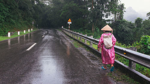 Woman walking on wet road during rainy season