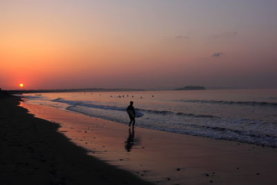 Silhouette of people on beach at sunset