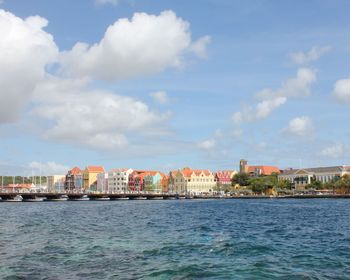 Sea by buildings against sky in city