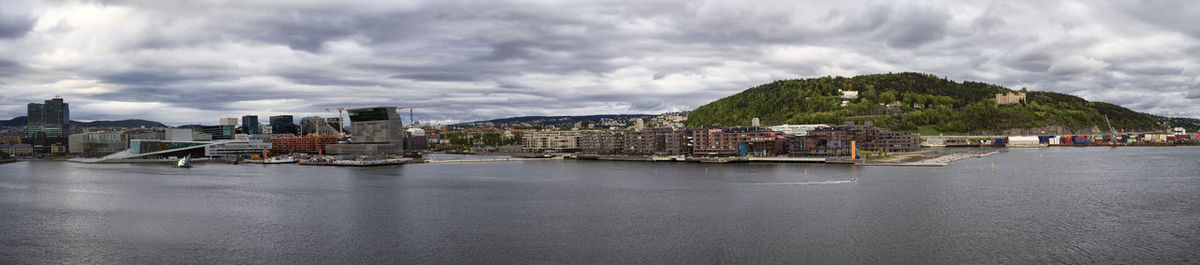 Buildings by river against sky in city