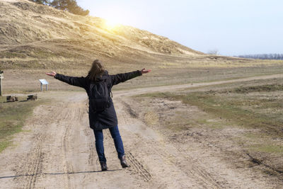 Rear view of man with arms outstretched standing on landscape
