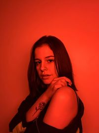 Portrait of beautiful young woman against red background