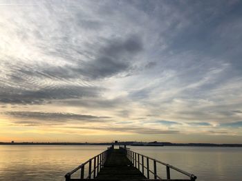 Pier over sea against sky during sunset