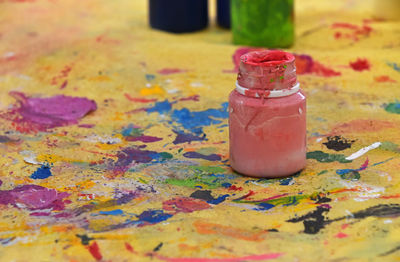 Close-up of paint bottle on messy paper