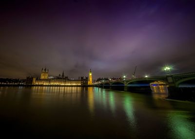 Westminster bridge by thames river against sky in city at night