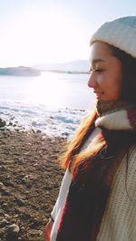 Young woman standing at beach against sky during winter