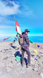Portrait of hiker standing with indonesian flag at mount semeru peak