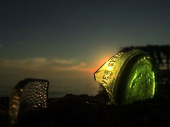 Close-up of illuminated bottle against sky during sunset
