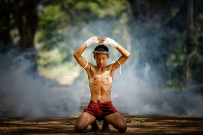 Full length of shirtless warrior in forest