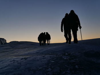 Silhouette people walking on snow covered land