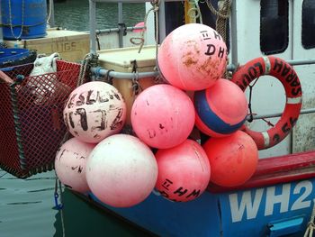 Close-up of buoys and inflatable ring hanging on fishing boat