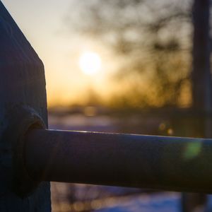 Close-up of metal fence against sunset sky