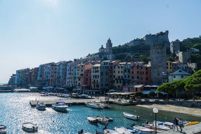 Boats moored in sea against buildings in city