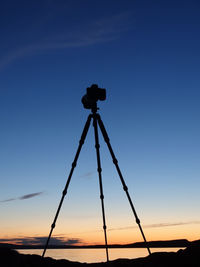 Low angle view of silhouette tripod and camera against sky during sunset