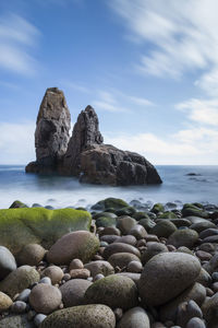 View of rocks in calm sea against the sky