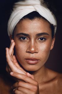 Close-up portrait of young woman against black background