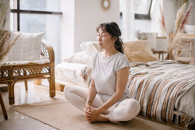 Portrait of young woman using mobile phone while sitting on sofa at home