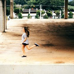 Side view of young woman running on concrete floor