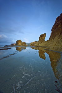 Rock formations in water against sky