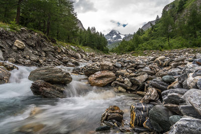 Scenic view of river flowing through rocks against sky