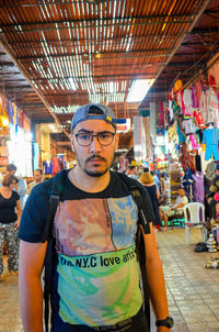 Portrait of young man standing at illuminated market