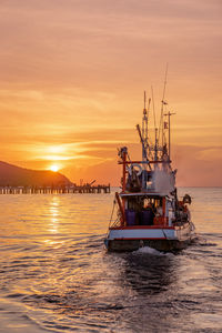 Boat sailing in sea against sky during sunset